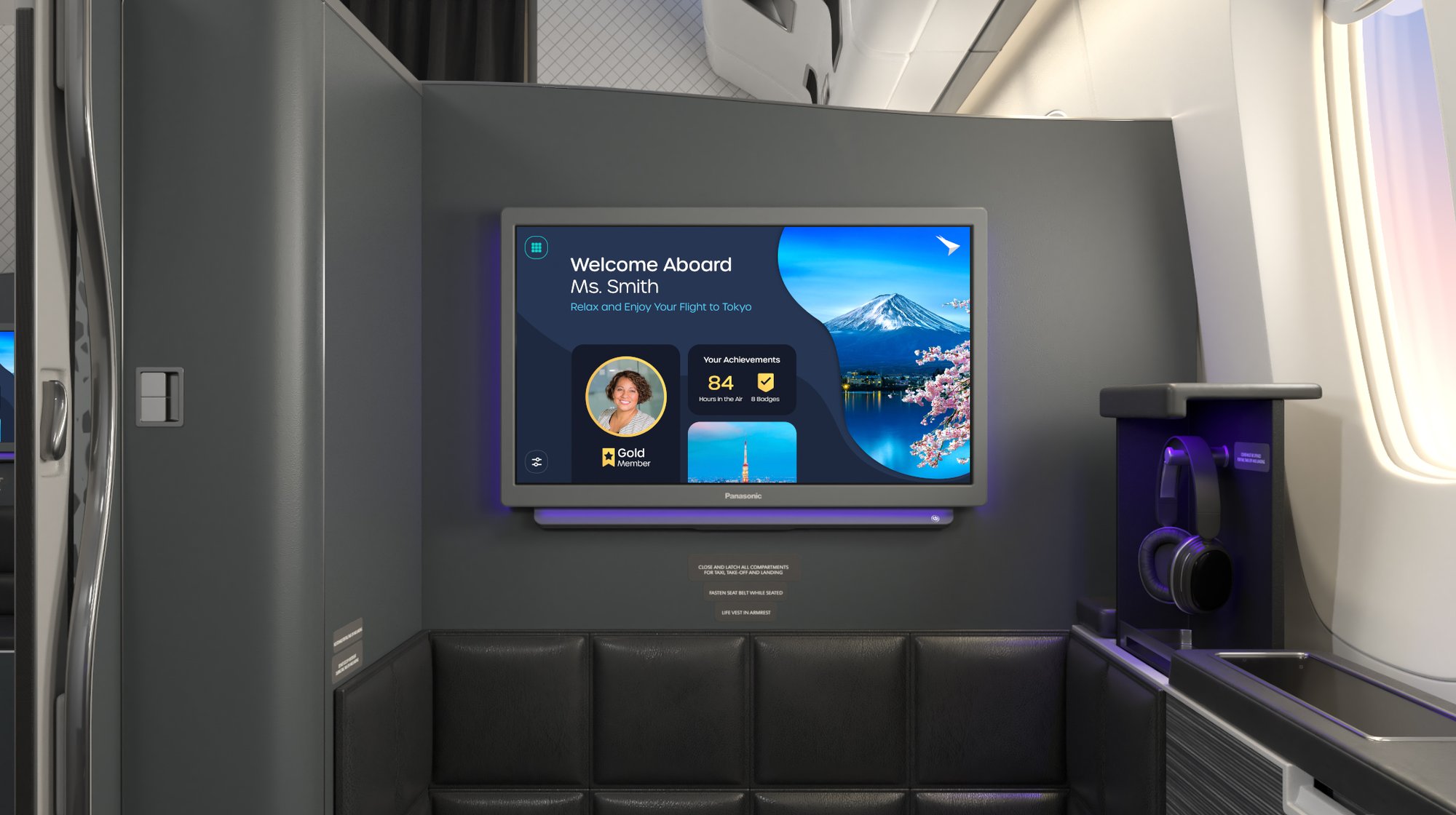 A modern airplane's first-class seat with a screen displaying a welcome message for the passenger