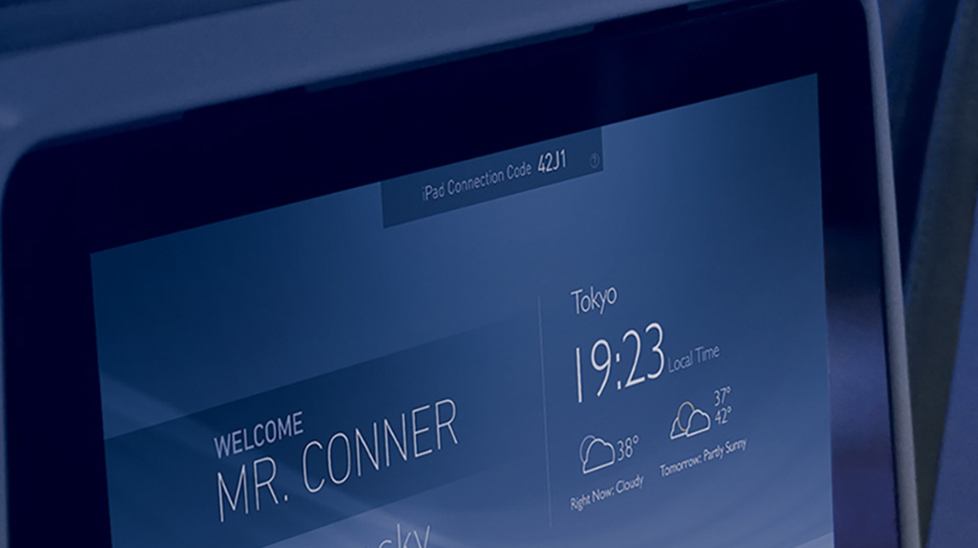 Close-up of an airplane seat screen displaying a passenger welcome message and flight information