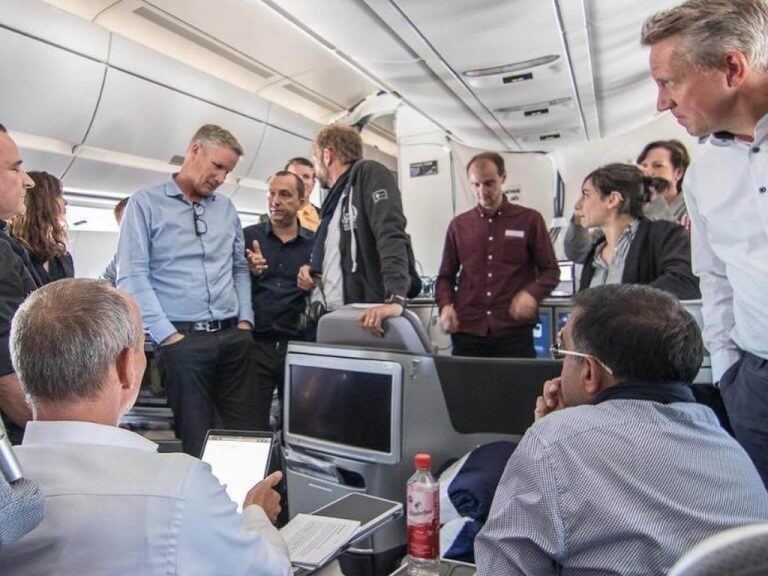 A group of people having a discussion in an airplane cabin
