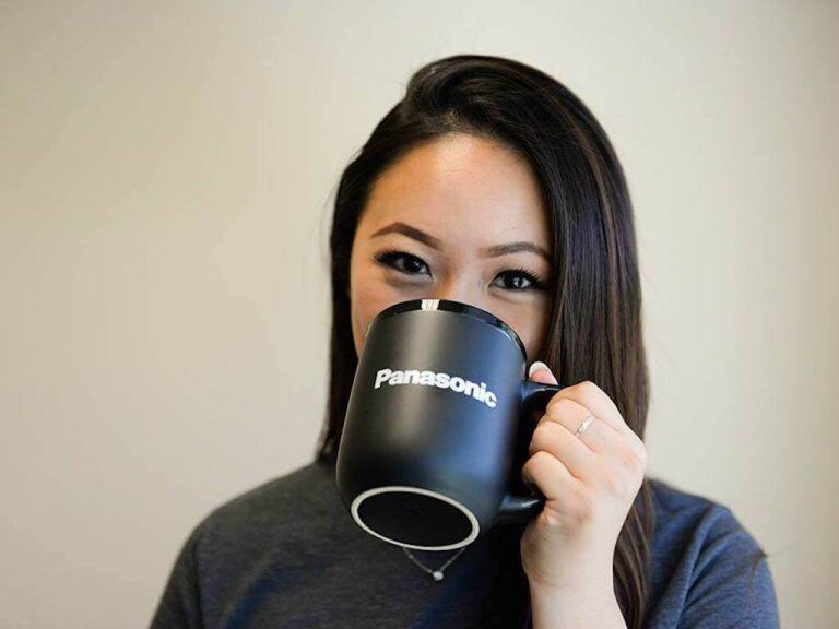 Person holding black Panasonic mug in front of face