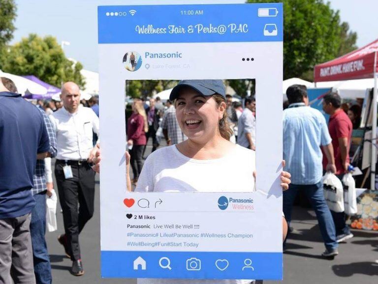 Person holding a large social media post cutout at an outdoor wellness fair