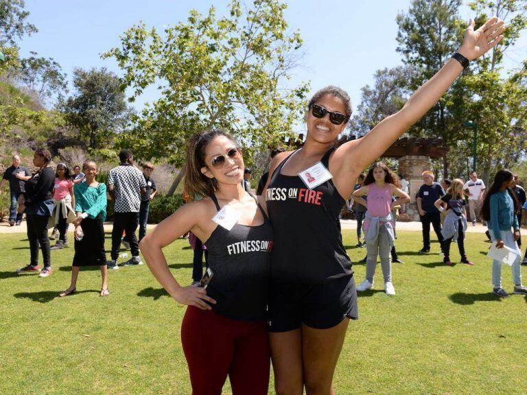 Two women posing in a park with others in the background
