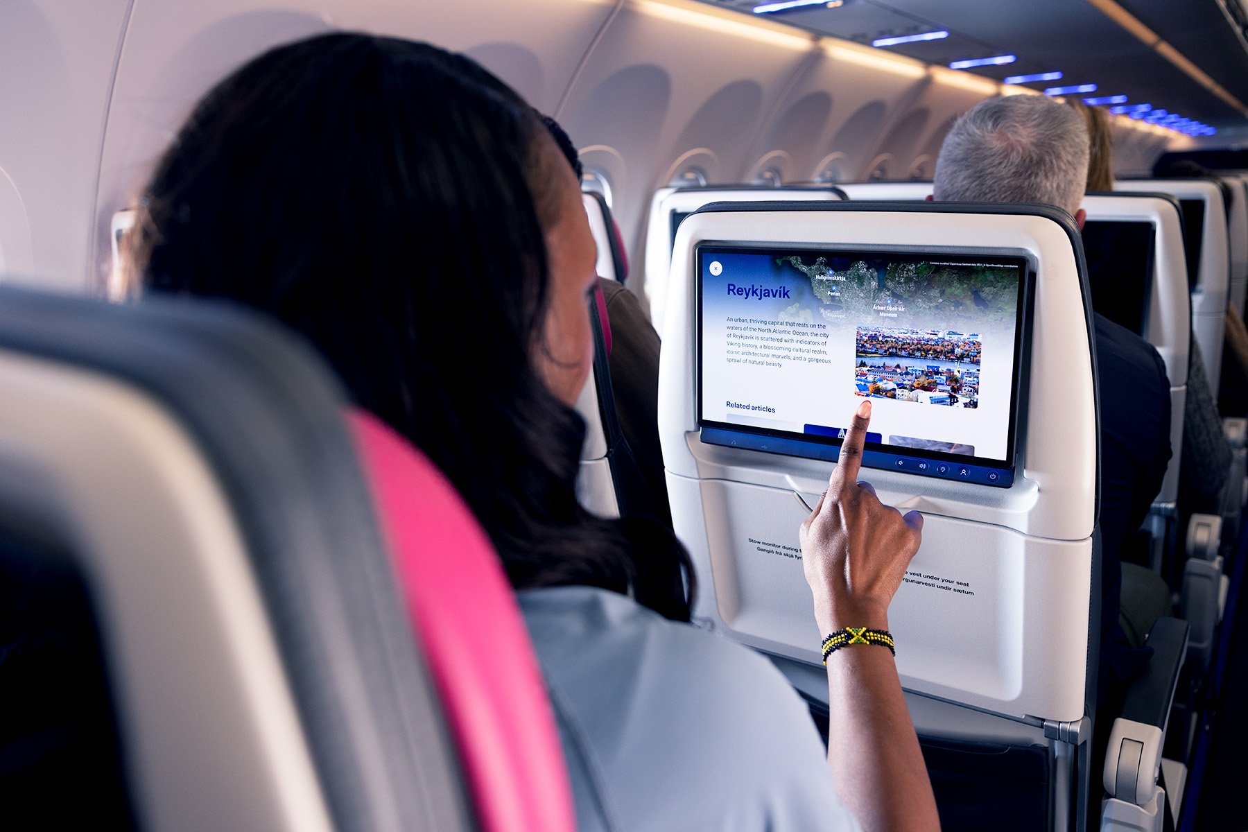 A passenger in an airplane using a feature on the seatback entertainment system.
