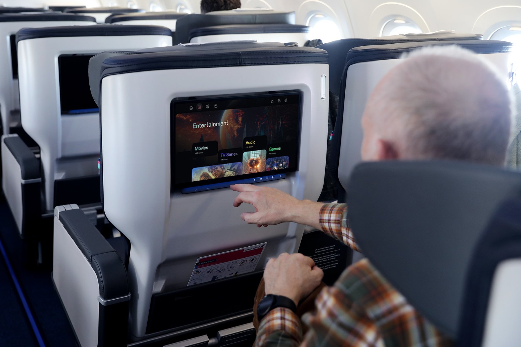A passenger in an airplane using the seatback entertainment system.