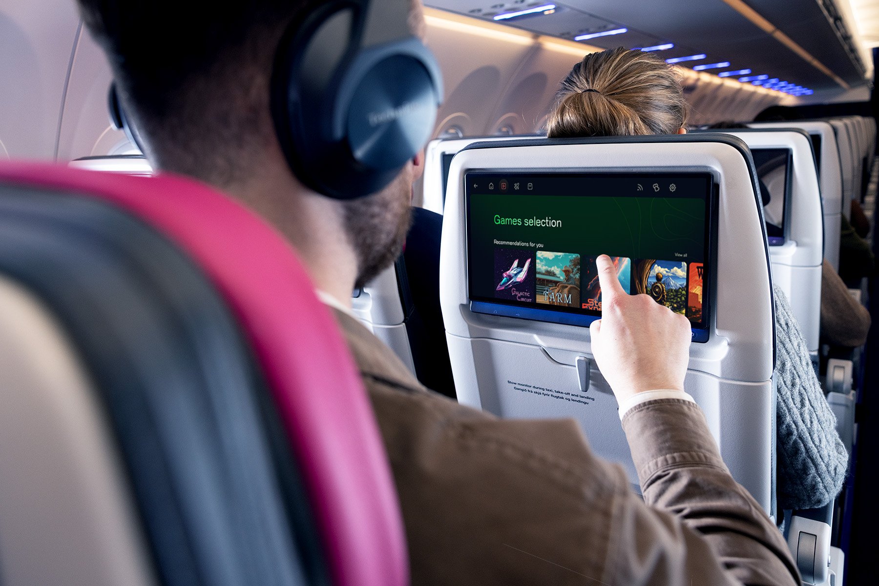 A passenger in an airplane using the gaming feature on the seatback entertainment system.