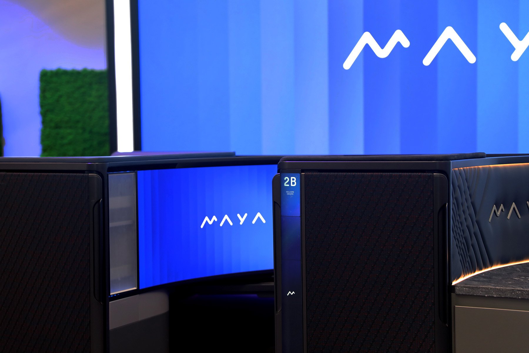 Partial left view of the MAYA seat with the word MAYA displayed on the curved screen