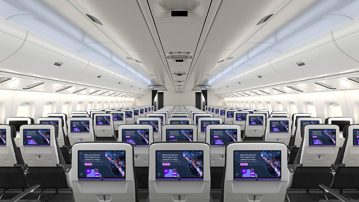 Interior of an airplane's economy class with personal screens on the back of each seat