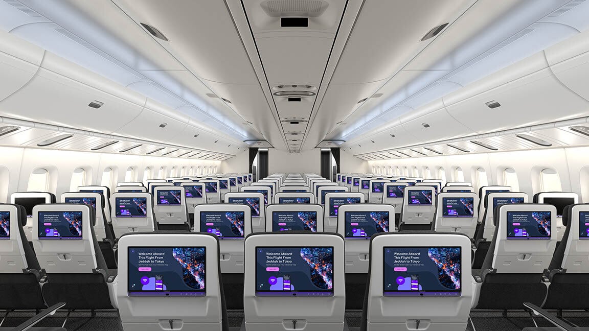 Interior of an airplane cabin with rows of seats and individual screens on each seat back