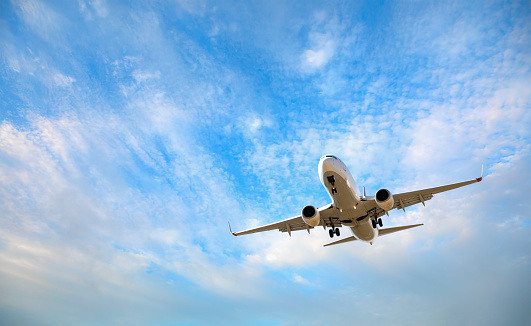 Airplane flying against a blue, partly cloudy sky